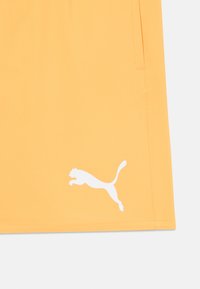 Puma kratke hlače v živahni oranžni tkanini z gladko teksturo. Na spodnjem levem kotu se nahaja bel logotip skakajoče mačke.
