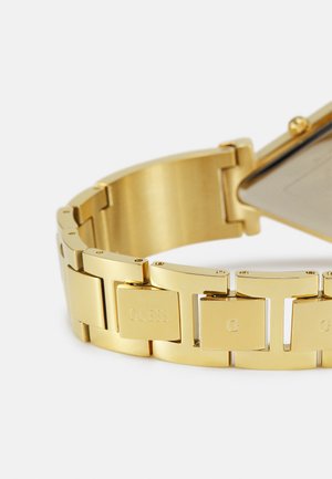 Zlaté kovové hodinky s náramkom spojeným z článkov. Majú obdĺžnikovú ciferník a vyrytú značkovú značku na článkoch náramku. Hladký povrch.