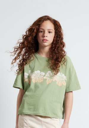 T-shirt en coton vert avec un motif floral blanc et pêche sur la poitrine, avec une coupe décontractée et des manches courtes.