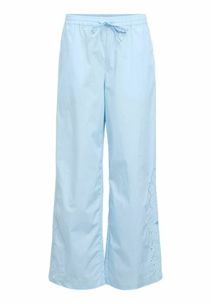 Pantalon ample bleu clair avec taille élastique et cordon de serrage, présentant des détails en dentelle découpée le long de la partie inférieure externe des jambes.