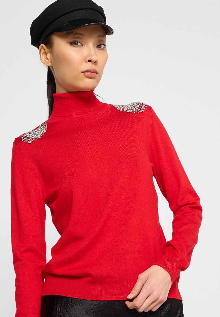 Maglione rosso a collo alto con maniche lunghe, caratterizzato da dettagli gioiello sulle spalle, realizzato in un morbido tessuto testurizzato.