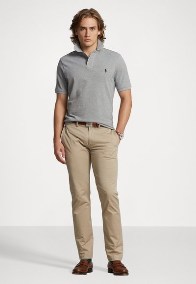 Gray short-sleeve polo shirt with a collar and embroidered logo, paired with light beige trousers and brown leather shoes.