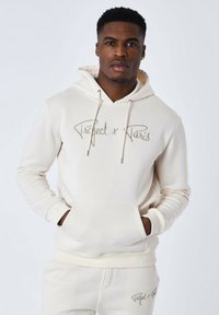 Hoodie color crema realizzato in tessuto morbido; presenta una tasca frontale, cappuccio con cordino e logo ricamato "Project x Paris" in marrone chiaro.