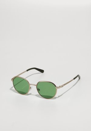 Ochelari de soare cu nuanță verde, cu un ramă subțire din metal auriu, lentile ovale, brațe negre și un element de design subtil pe brațe.