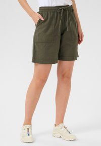 Shorts vert olive en tissu texturé, dotés d'une taille élastique avec cordon de serrage, de poches latérales et d'une coupe décontractée.