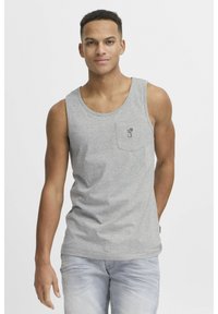 Tricou de bumbac gri fără mâneci, cu guler rotund și buzunar, având un grafic simplu imprimat. Purtați cu blugi decolorati de culoare albastră deschisă.