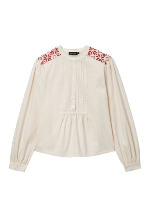 Blouse crème à manches longues avec accents brodés rouges aux épaules, panneau frontal plissé, encolure arrondie, et poignets de manches élastiqués.