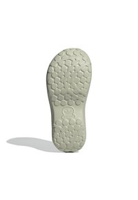 Ljust grå gummisula med en texturerad yta som har cirkulära mönster och en central logotyp. Släta kanter och rundad form.