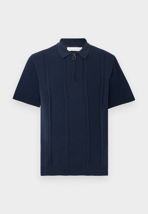 Polo de punto de manga corta en azul marino con rayas verticales texturizadas y cremallera frontal con una lengüeta circular.