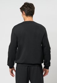 Hanorac negru cu mâneci lungi, manșete și tiv cu nervuri, design minimalist, textură moale și fără mărci sau modele vizibile.