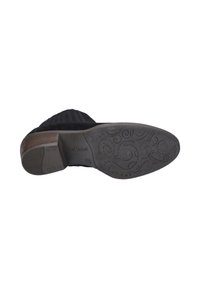 Bottine en daim noir avec une semelle texturée, dotée d'un talon en bois et d'un motif tourbillonnant au fond. Remarquable par son design robuste et son adhérence.