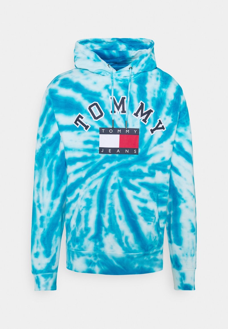 Huvtröja i blått tie-dye-mönster, med en logotyp framtill med texten "TOMMY" och en rektangulär design i röd, vit och blå.