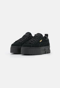 Schwarze Wildleder-Plattform-Sneaker mit runder Spitze, dicker Gummisohle, flachen Schnürsenkeln, geprägtem Branding und einer Zugschlaufe an der Ferse.