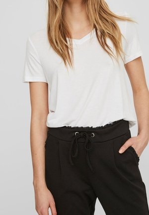 Vit t-shirt med v-ringning ihopparad med svarta joggerbyxor med resår i midjan och dragsko, sidfickor och en avslappnad passform.