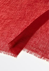 Deep red lightweight fabric with a crinkled texture and fringed edges, laid flat with a folded section on a white background.