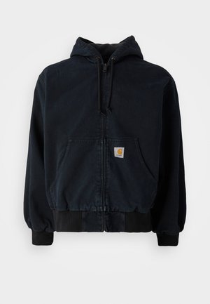 Black zip-up hoodie with front pockets, drawstring hood, ribbed cuffs and hem, featuring a small rectangular yellow logo patch on the pocket.