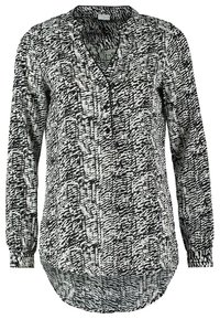 Blouse à manches longues avec un motif abstrait noir et blanc, col en V, trois boutons sur le devant et un ourlet arrondi.