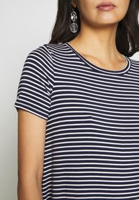 Niebiesko-biały paskowany t-shirt z krótkim rękawem i okrągłym dekoltem, o gładkiej fakturze i luźnym kroju.