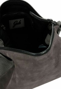 Borsa a tracolla in suede grigio scuro aperta, con interno nero, tasca interna con zip visibile e etichetta in pelle cucita all'interno.