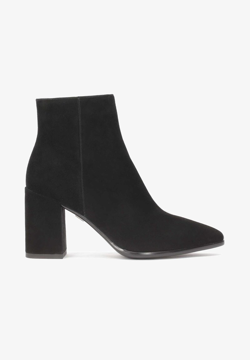 Bottine noire en suède avec un bout pointu et un talon bloc, montrée de profil sur fond blanc.