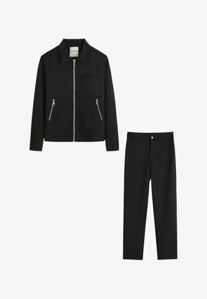 Veste noire avec fermeture éclair frontale et poches zippées, associée à un pantalon noir assorti avec fermeture par bouton.