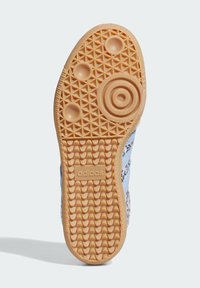 Adidas Schuhsohle mit strukturiertem Muster, kreisförmigen Griffen und einer hellen Tan-Farbe; enthält das Markenlogo und ein rautenförmiges Profildesign.