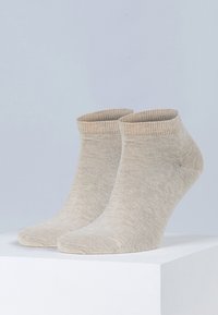 Beige ankelstrømper laget av myk, ribbet stoff, med sømløs tå og en subtil fargegradient ved mansjetten.
