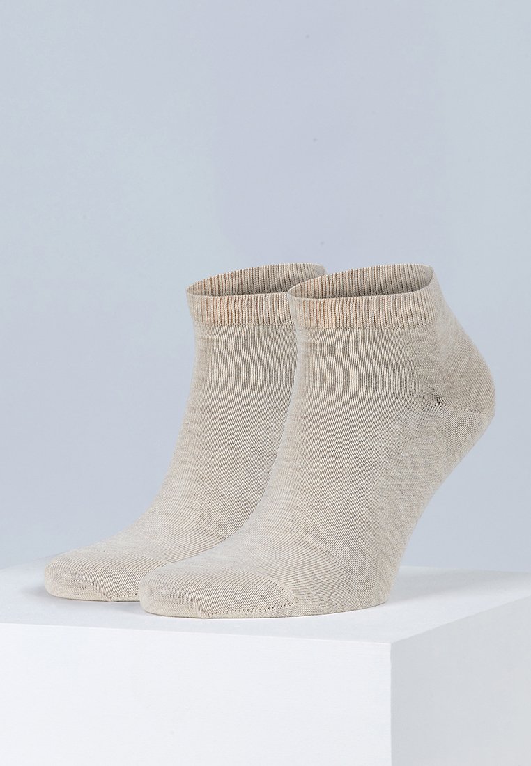 Beige ankelstrømper laget av myk, ribbet stoff, med sømløs tå og en subtil fargegradient ved mansjetten.