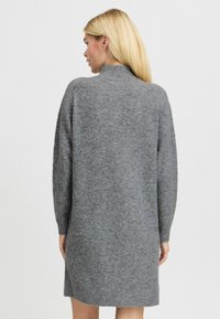 Rochie tricotată gri, cu guler înalt și mâneci lungi. Prezintă o croială lejeră și o textură moale, ajungând până la mijlocul coapselor.