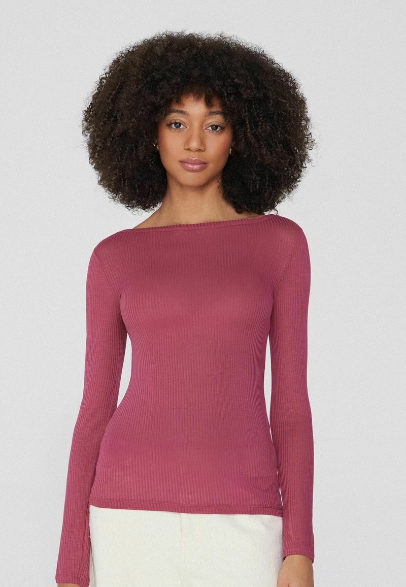 Langärmliges, geripptes Oberteil in Mauve mit einem Bootsausschnitt und figurbetonter Silhouette. Sanfte Textur mit subtiler Schattierung.