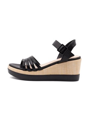 Black wedge sandal with black synthetic straps and a textured, natural woven platform. Adjustable ankle strap with a metal buckle.