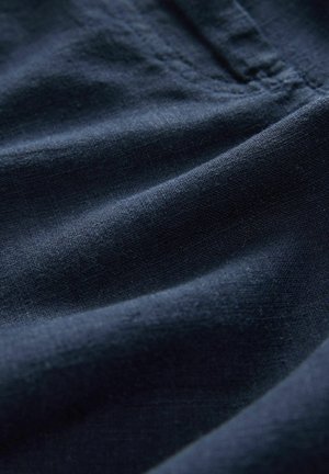 Jūras zila auduma ar mīkstu, teksturētu virsmu, kas raksturota ar smalkām krokām un locījumiem. Materiāls šķiet viegls un austs.