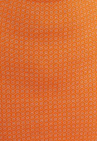 Tissu orange avec un motif géométrique blanc, présentant des formes en zigzag interconnectées ; texture lisse.