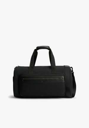 Czarna prostokątna torba podróżna z podwójnymi górnymi uchwytami, przednią kieszenią na zamek oraz regulowanym paskiem na ramię.