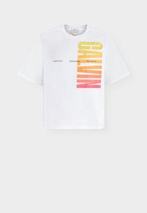 Biała koszulka z krótkim rękawem z pionowym gradientowym napisem "CALVIN" od żółtego do czerwonego oraz mniejszym poziomym napisem "Calvin Klein New York City Established 1968".