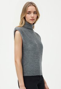 Grauer ärmelloser Rollkragenpullover aus weichem Material, mit taillierter Passform und geripptem Saum, der eine schlichte und klare Silhouette präsentiert.