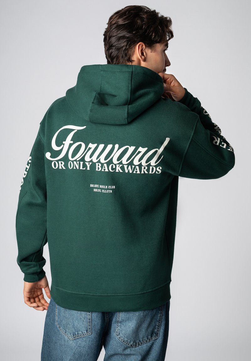 Dunkelgrüner Hoodie aus Baumwolle mit großem weißem Schriftzug auf dem Rücken, langen Ärmeln und einer Kängurutasche vorne.