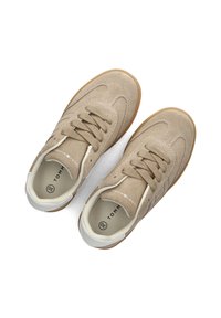 Beżowe zamszowe sneakersy z teksturowanym wierzchem, okrągłym noskiem i sznurowaniem. Białe akcenty na języku i pięcie, gumowa podeszwa.