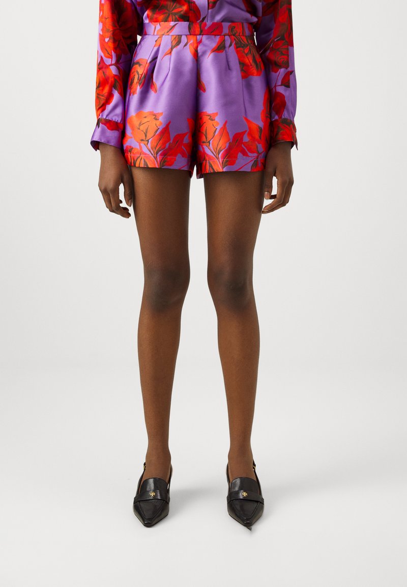 Satin shorts in purple with red floral pattern, featuring a high waist, pleats, and black pointed loafers with gold accents.