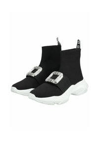 Des bottines noires en maille présentent une semelle blanche épaisse, un grand accent de boucle en argent et une languette de talon noire contrastante avec l'étiquette de la marque.
