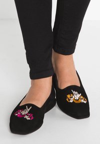 Mocassini in suede nero con ricami floreali e di tigre, punta affusolata e design a intaglio nella parte superiore. Suola bassa e piatta.