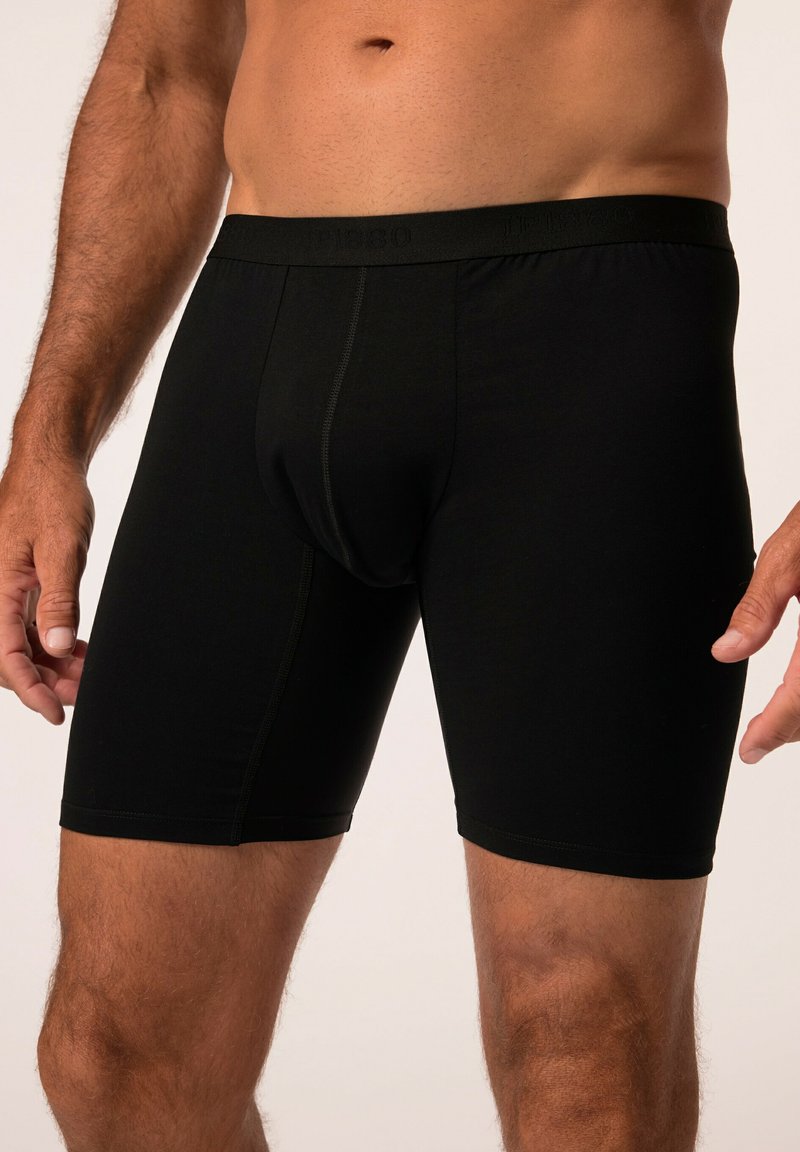 Boxer-briefs noirs en tissu doux et extensible. Présentent un ajustement près du corps, une taille élastique et des coutures minimales pour le confort.