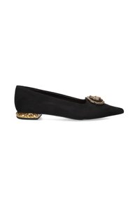 Zapato plano de ante negro con punta afilada, adornado con un acento decorativo en tono dorado y un detalle de tacón dorado con tachuelas.