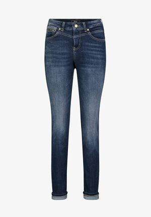 Ciemnoniebieskie rurki jeans z podwiniętymi mankietami, zapięciem na guzik i zamek błyskawiczny z przodu oraz widocznym wyblaknięciem na udach i kolanach.