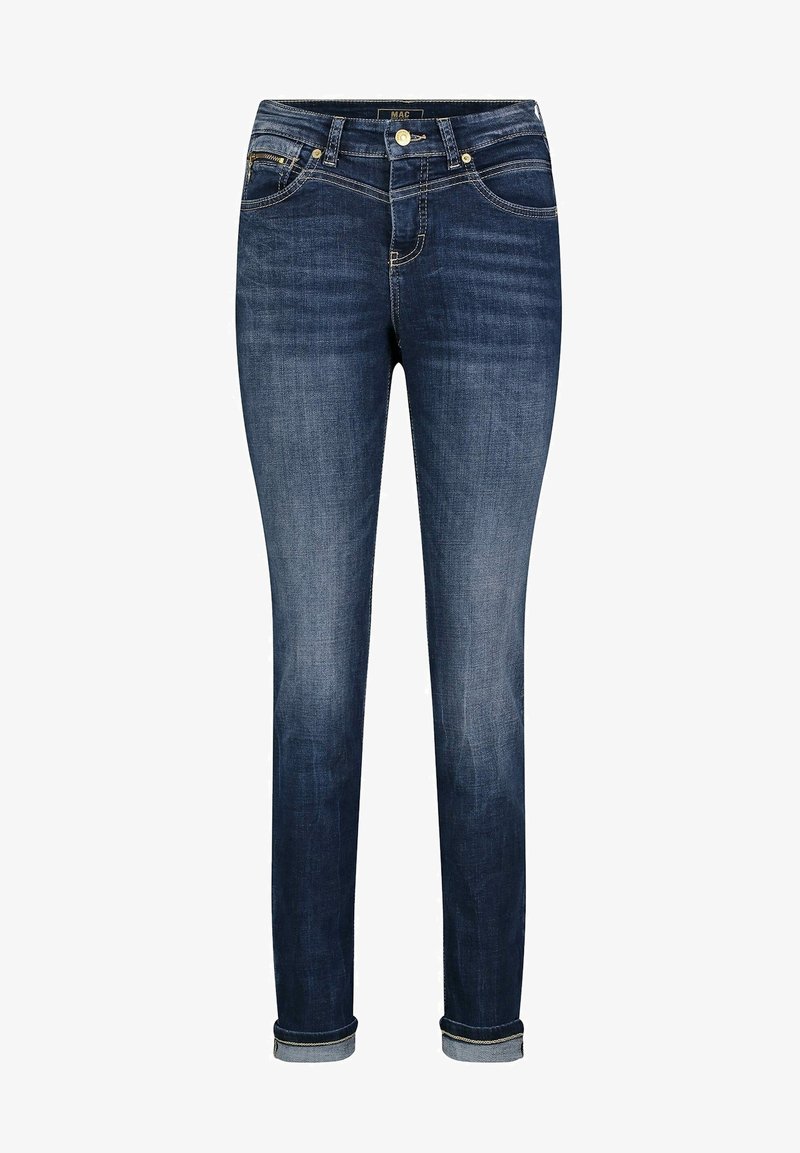 Jean skinny bleu foncé avec ourlets roulés, fermeture avant par bouton et zip, avec des décolorations visibles sur les cuisses et les genoux.