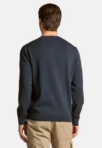 Maglione in maglia blu scuro con maniche lunghe, scollo a giro e polsini e orlo a coste. Il materiale sembra morbido e ben strutturato.