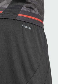 Pantalones cortos deportivos negros con una tela suave y detalles de malla, una franja roja y un logo que dice "A R O R E D Y" cerca de la cinturilla.