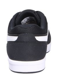 Black athletic shoe with a textured fabric upper, white rubber sole, and contrasting white stripe along the heel. Rear view shows padded collar.