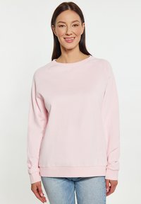 Lichtroze sweatshirt met ronde hals, geribde manchetten en een ontspannen pasvorm. Gemaakt van een zachte stof, met raglanmouwen en minimale naden.