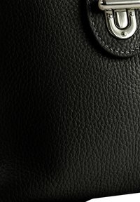 Schwarze Ledertasche mit strukturierter Oberfläche, ausgestattet mit einem silbernen Metallverschluss und einer Steppnaht, die ein schlankes, abgerundetes Design präsentiert.